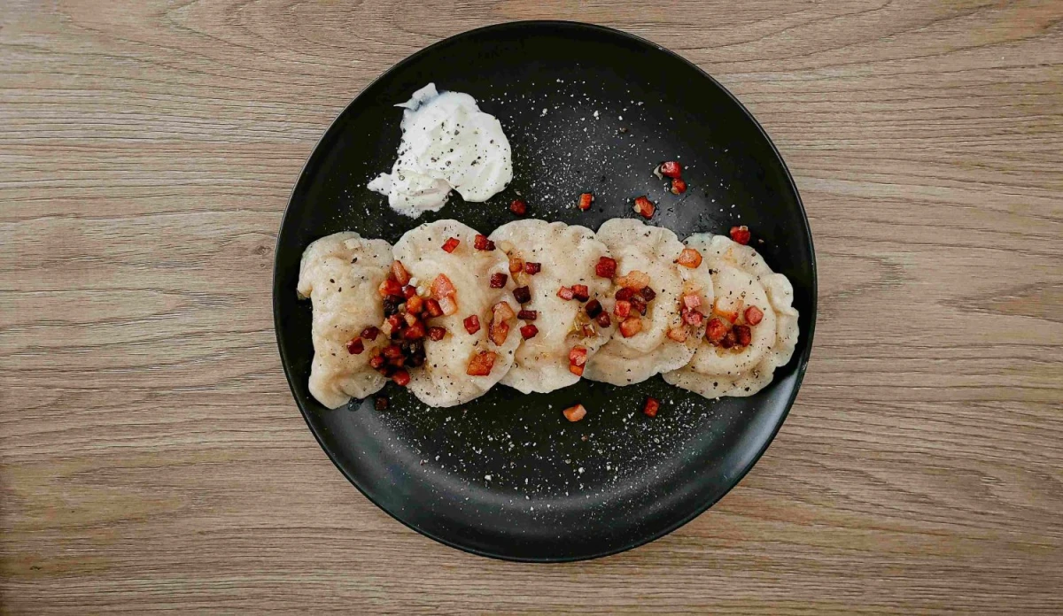 Pierogi ze skwarkami z boczku, śmietaną, posypane świeżo zmielonym pieprzem